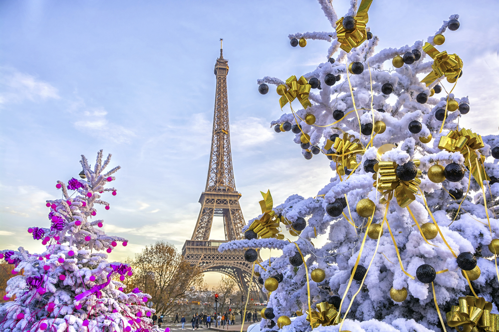Eiffelturm in Paris im Winter mit schneebedeckten, festlich geschmückten Bäumen im Vordergrund